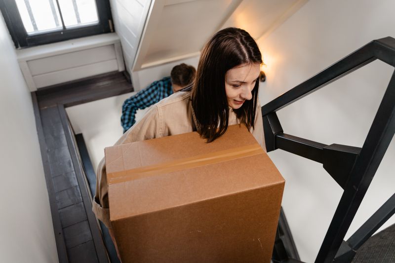 Couple carrying a large box up a staircase during a move