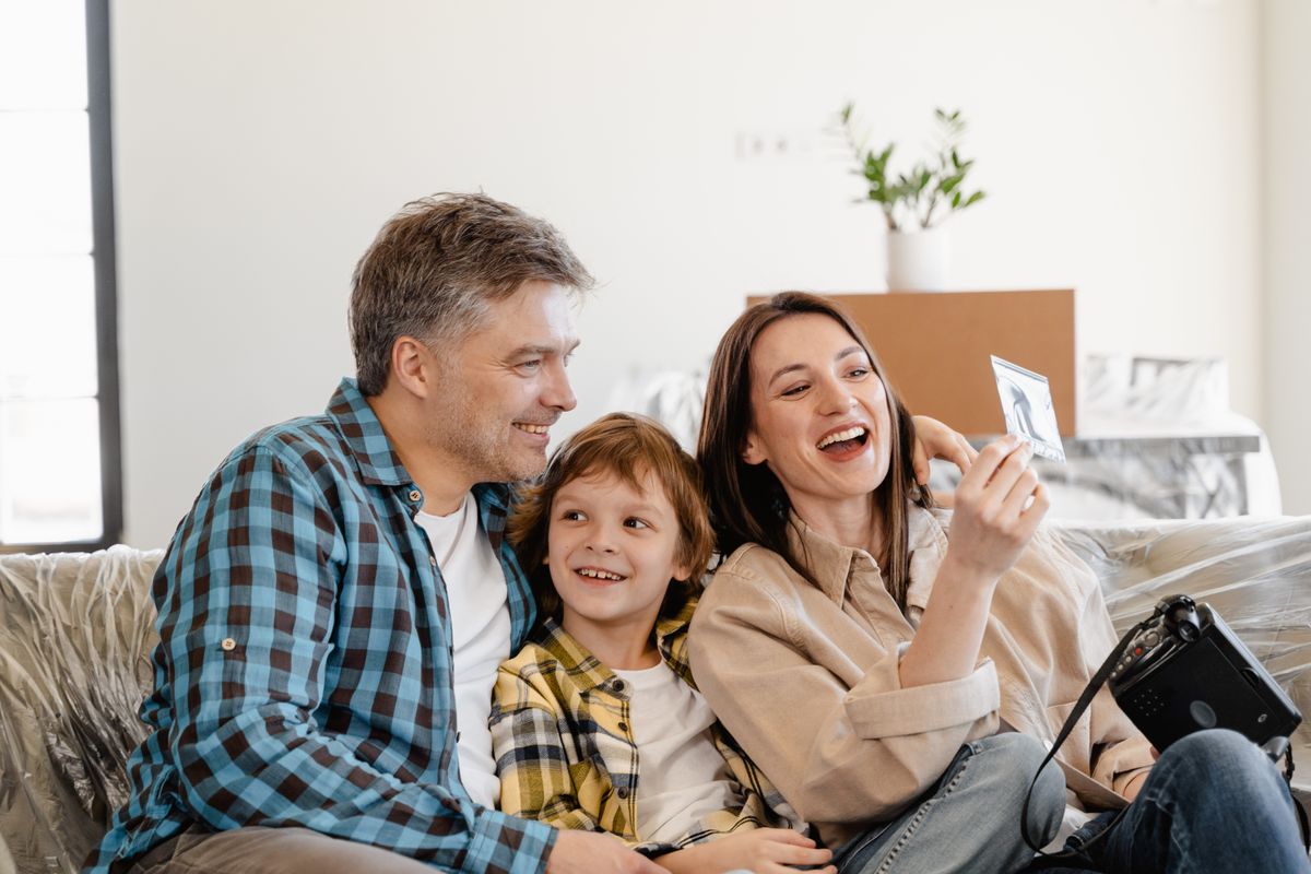 Happy family relaxing on a couch surrounded by moving boxes in their new home